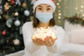 Lights in hands of asian woman in face mask and santa hat, new life of coronavirus pandemic at New Year or Christmas Royalty Free Stock Photo