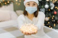 Lights in hands of asian woman in face mask and santa hat, new life of coronavirus pandemic at New Year or Christmas Royalty Free Stock Photo