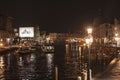 lights illuminate people on boats in the waterway near old buildings