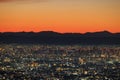 Lights from sprawling city with orange dawn glow over distant mountains