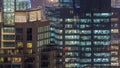 Lights in windows of modern multiple story office building in urban setting at night timelapse