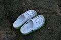 Smudged plastic white shoes with holes on the rocks at the beach in china.