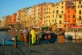 Men working to collect garbage at dawn on the pier of the port overlooking the colored buildings of Portovenere