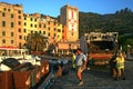 Men working to collect garbage at dawn on the pier of the port overlooking the colored buildings of Portovenere