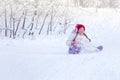 A liitle child rides an iceboat in a snow-covered forest. A little girl sitting on her ass slides down a snow slide. Concept of Royalty Free Stock Photo