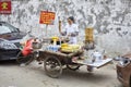 Woman prepares and sells breakfast food from street stall.