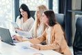 Likable young female office workers sitting at the meeting room and discussing their joint business project using