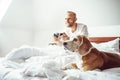Like a child: udult breaded man waked up and plays PC games don`t stands up from bed.His beagle dog watching the game with very in