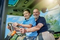 Like father, like son. Low angle portrait of a male farmer and his son inside the cockpit of a modern tractor. Royalty Free Stock Photo