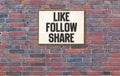 Like, Follow and Share in light box on brick wall