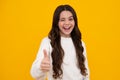 Like it. Portrait of joyful teenage child girl showing thumbs up and smiling, yellow background with copy space. Excited Royalty Free Stock Photo