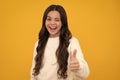 Like it. Portrait of joyful teenage child girl showing thumbs up and smiling, yellow background with copy space. Excited Royalty Free Stock Photo