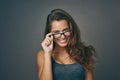 Like what you see. Studio shot of an attractive young woman peering over her glasses against a grey background. Royalty Free Stock Photo