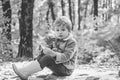 He likes hiking. Kid sit on plaid forest picnic. Child relax in autumn forest. Forest school is outdoor education. Visit