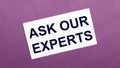 On a lilac background, a white card with the words ASK OUR EXPERTS Royalty Free Stock Photo