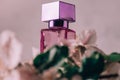 Lilac bottle of eau de toilette or perfume with square cap on light surface with apple flowers