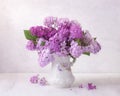 Lilac bouquet in the faience jug on a white wooden table. Soft focus