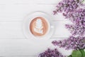 Lilac, coffee with latte art on light wooden table. Romantic morning.Flat lay