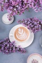 Lilac, coffee with latte art and marshmallow on gray wooden table. Romantic morning. Flat lay
