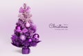 A lilac-colored Christmas tree stands on a lilac background. Pink lilac and purple balls hang on the Christmas tree.