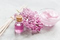 Lilac cosmetics with flowers and spa set on stone table background