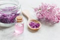 Lilac cosmetics with flowers and spa set on stone table background