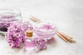 Lilac cosmetics with flowers and spa set on stone table background