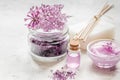 Lilac cosmetics with flowers and spa set on stone table background