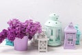 Lilac flowers and brigh lanterns on white wooden background