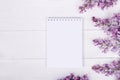 Lilac flowers and notepad on white background. Spring mood. Top view