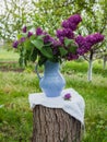 Lilac flowers in old blue porcelain vase or decanter on a wooden stump. Spring background in a garden Royalty Free Stock Photo