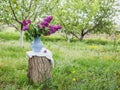 Lilac flowers in old blue porcelain vase or decanter on a wooden stump. Spring background in a garden Royalty Free Stock Photo