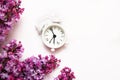 Lilac flowers with vintage tiny alarm clock on white background. Spring morning concept. Top view, flat lay Royalty Free Stock Photo