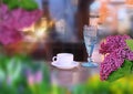 lilac flowers white  cup of coffee and blue glass of wine on wooden table at street cafe sunlight reflection on windows city urba Royalty Free Stock Photo
