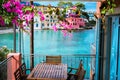 Lilac fuchsia blossom flower over hotel veranda in front of turquoise colored bay of Mediterranean sea and beautiful Royalty Free Stock Photo