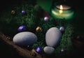 Lilac, golden stone lies in the bark of a tree with green moss, gray stones and a burning candle on a green Royalty Free Stock Photo