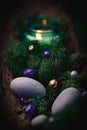 Lilac, golden stone lies in the bark of a tree with moss, gray stones and a burning candle on a black Royalty Free Stock Photo