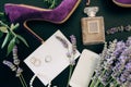 Lilac high heel shoe, a bottle of perfume, a smartphone, jewelry and flowers on a green background