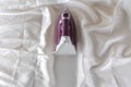 Lilac iron on a piece of white crumpled fabric. ironing clothes. household electrical appliances. view from above