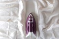 Lilac iron on a piece of white crumpled fabric. ironing clothes. household electrical appliances. view from above