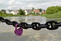 The lilac lock hangs on a chain against the river