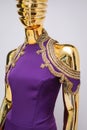 Long, lilac designer, evening, women`s dress handmade on gold, glossy mannequin. With white and gold bead ornament. Isolated on gr