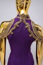 Long, lilac designer, evening, women`s dress handmade on gold, glossy mannequin. With white and gold bead ornament. Isolated on gr