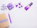 Lilac perfume, a gift, a notebook, paper clips and a pen lie on a light background. Flat lay with copy space. Female concept