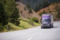 Lilac semi truck with aluminum trailer is moving along winding h Royalty Free Stock Photo