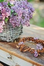 Lilacs in basket and handmade wreath on vintage bureau in spring garden