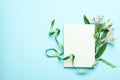 Lilies, green ribbon and blank sheet on blue background Royalty Free Stock Photo