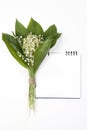 Lilly of the valley flowers and leaves bouquet with sketchpad