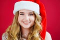 a lilt beautiful woman in a Santa Claus hat on a red background. Royalty Free Stock Photo