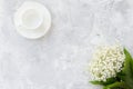 Lily of the valley bouquet and empty cup for coffee on a concrete texture Royalty Free Stock Photo